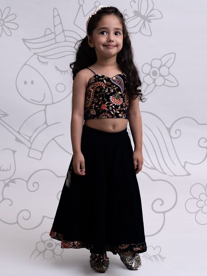 A black velvet skirt paired with a vibrant, embroidered crop top for a stylish and comfortable ethnic look.