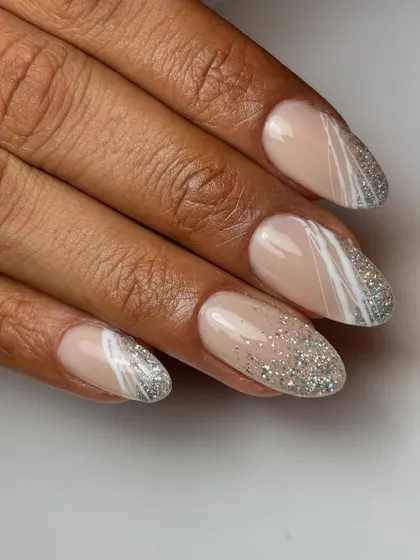 All about the glitter. This elegant design features a falling glitter effect over a nude base, paired with abstract white spider gel lines for a modern touch.
