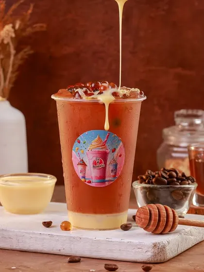 A delicious-looking iced coffee or bubble tea with a creamy drizzle. The warm, earthy tones of the background give this shot a cozy and comforting feel.