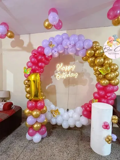 A colorful balloon ring in pink, purple, and gold for a first birthday celebration at home.