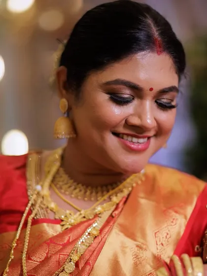 A classic South Indian reception look. This bride is wearing a beautiful Kanjivaram saree, and her makeup features a warm, glowing base with soft smokey eyes and a traditional low bun hairstyle.