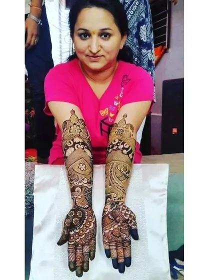 This client is happy with her full-coverage bridal mehandi. The design features a mix of traditional motifs that extend from her fingers to her elbows.