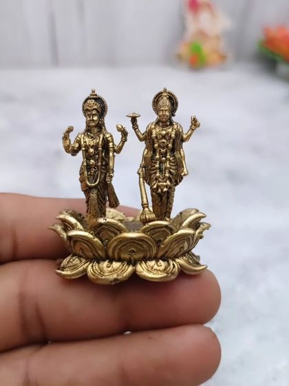 A hand-held view of the brass Lakshmi-Vishnu idol, showing its small size which makes it a perfect return gift or a personal keepsake.