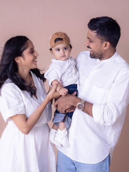 A candid and interactive family moment in the studio. The parents' focus is entirely on their little one, creating a natural and loving family portrait that feels unstaged and real.