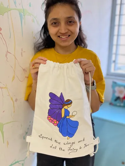 A participant shows off the fairy-themed backpack she painted. This workshop is perfect for unleashing your creativity on a functional item.