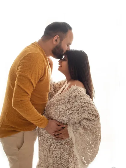 A sweet silhouette of a partner kissing his wife's forehead. The warm, natural light adds to the cozy feeling of this lifestyle maternity shoot.