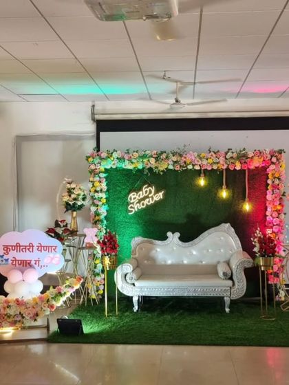 A Marathi-themed baby shower setup with a custom sign, a floral moon, and an elegant white diwan.