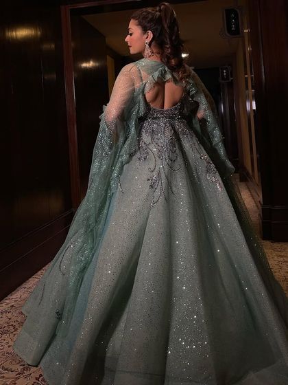 The back view of the mint organza gown, showcasing its dramatic cape veil that drapes across the shoulders. This adds an extra layer of elegance and movement to the dress.