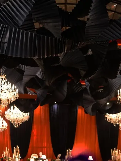 The dramatic ceiling treatment, with suspended black paper fans and crystal chandeliers, created a sense of texture and opulence.