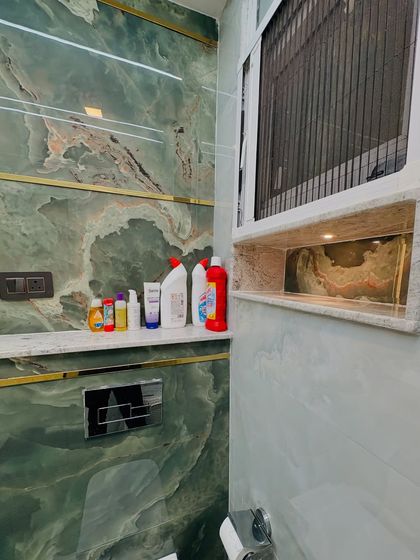 A close-up of the built-in niche in the shower area, a practical and stylish solution for storing toiletries. The green onyx-style tiles are a highlight.
