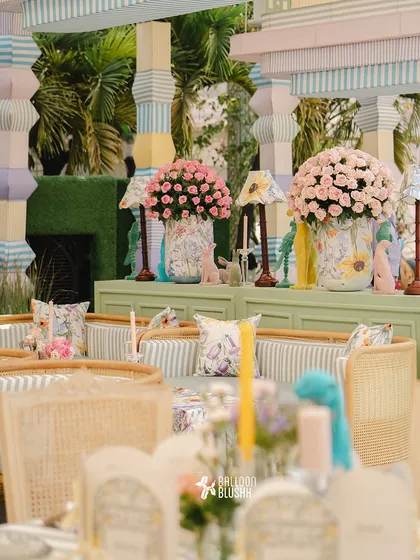 A seating area with pastel-striped cushions, floral-print lamps, and large bouquets of pink roses.