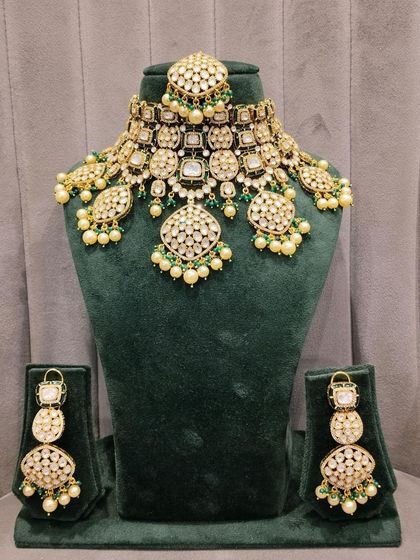 A stunning pachi kundan bridal set displayed on a mannequin. This set, featuring green bead drops and pearl accents, was the one chosen by our happy bride.