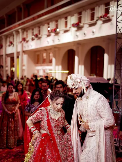 The couple walking together through the wedding venue. This candid shot captures a moment of movement and connection against the backdrop of their grand celebration.