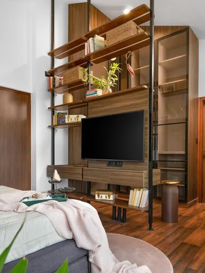In this master bedroom, the television and storage are integrated into a floor-to-ceiling unit that also acts as a room divider. The warm wood grain and sleek metal supports create a modern yet inviting piece that defines the space.