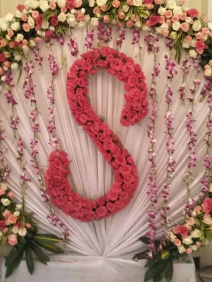 I also offer personalized decor, like this beautiful backdrop featuring the couple's initial 'S' made entirely of fresh pink roses. It's a great way to add a personal touch to your wedding stage.