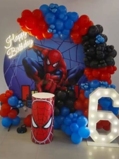 A compact and powerful Spider-Man theme for a 6th birthday. This decoration includes a circular backdrop, a red, blue, and black balloon arch, a themed pedestal, a neon sign, and a marquee number '6'.