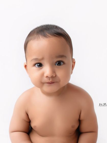 A close-up portrait of a baby boy with a curious expression.