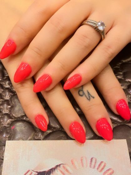 A classic set of almond-shaped nails in a bright, glossy coral-red. A perfect, vibrant color for any time of year.