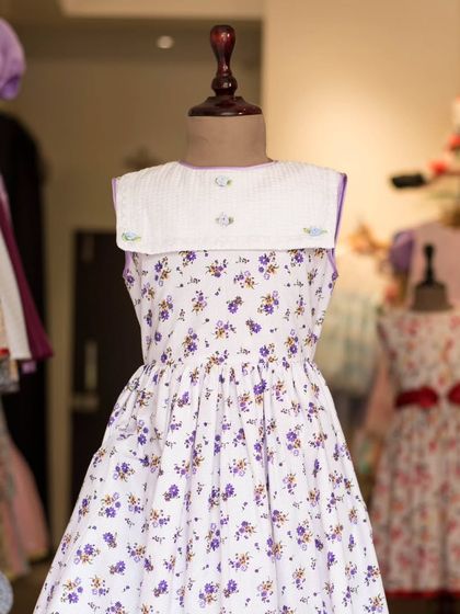 A beautiful floral dress with a contrasting white sailor collar. The delicate purple flowers and simple silhouette make this a charming and timeless piece.