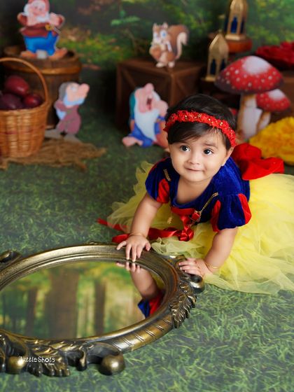 "Magic mirror, on the wall..." This little Snow White is fascinated by her own reflection in this charming shot from her fairytale photoshoot.