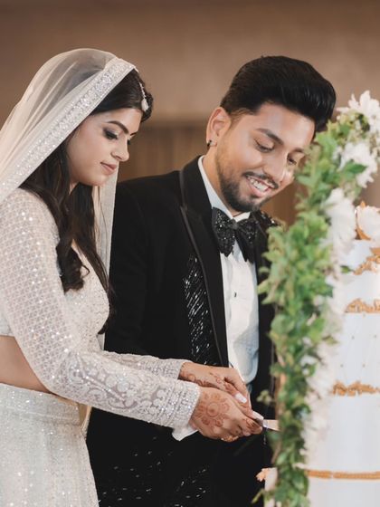 A close-up of the couple cutting their engagement cake. The groom's happy smile and their joint action make this a heartwarming shot.
