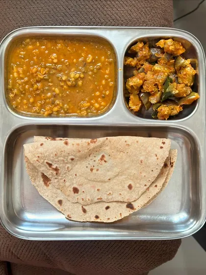 A simple meal of chapati, moong dal, and sautéed brinjal. This is a light and healthy lunch option that is easy to prepare.