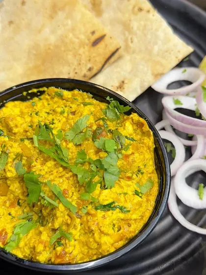 A bowl of my Paneer Bhurji, garnished with fresh coriander and served with sliced onions. It's a simple yet satisfying meal.