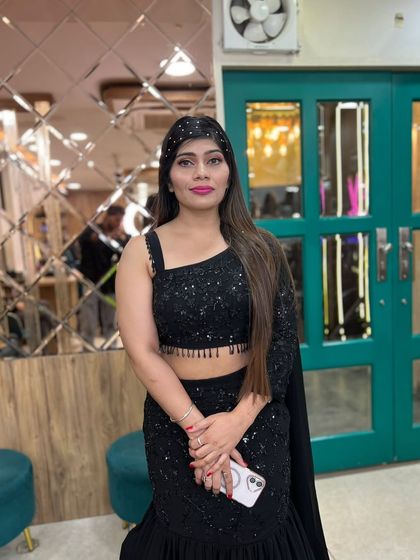 This client is party-ready in a stylish black ruffled saree. We kept her hair sleek and straight and added a pop of color with pink lipstick.