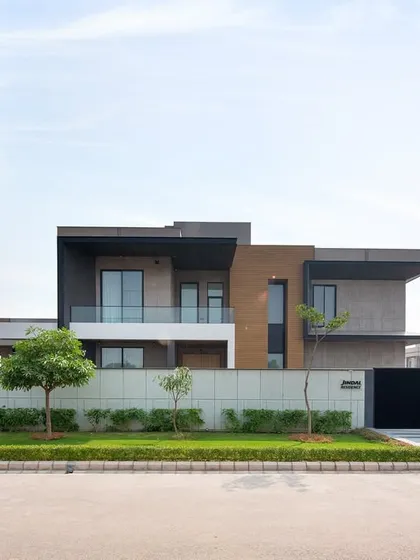 The front elevation of the Sonipat residence, showcasing its clean lines, cantilevered volumes, and a material palette of concrete and wood.
