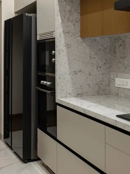A detail of the integrated appliances and sleek, dark refrigerator in this minimalist kitchen. Every element is designed to be functional yet unobtrusive, contributing to the overall sense of calm.
