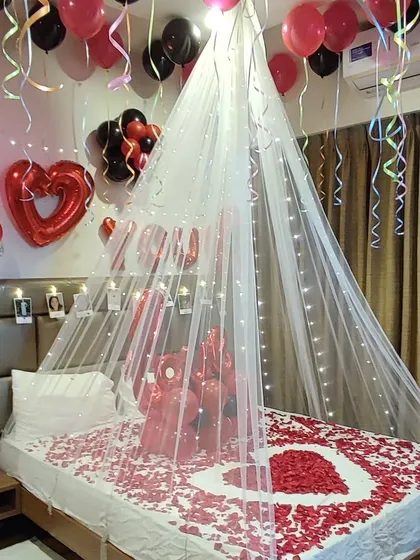 A personalized birthday surprise that includes cherished memories. Along with the red and black balloons and a light-up canopy, I added a string of photos above the headboard for a special touch.