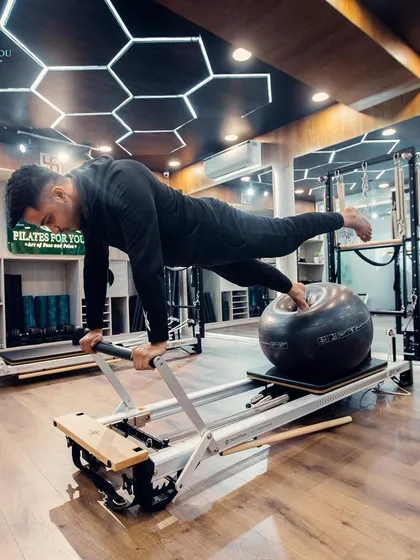Performance Pilates isn't just about flexibility. This single-leg high plank on the reformer, combined with a stability ball, is an advanced exercise for building immense core strength and balance.
