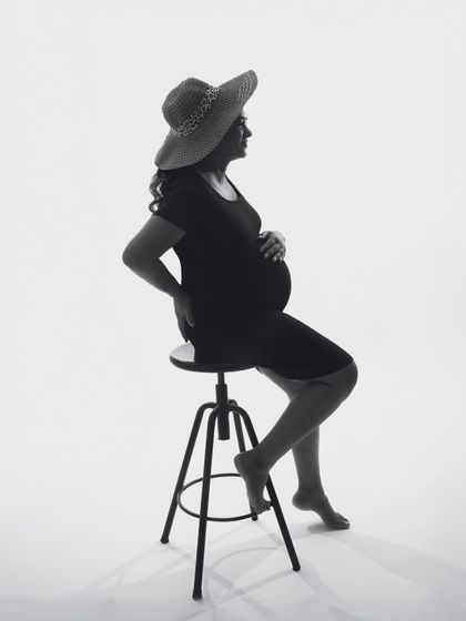 A minimalist and modern black and white silhouette. The simple composition with the hat and stool creates a chic and timeless portrait.
