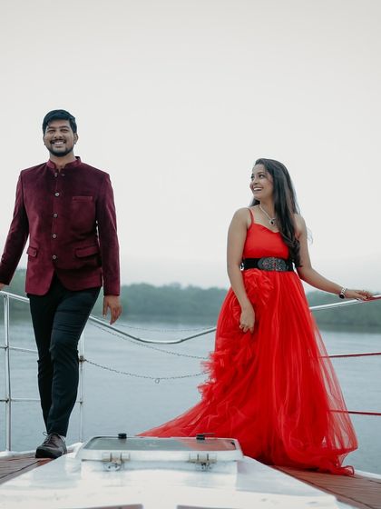 A stylish and modern pre-wedding shot on a boat. The red gown and the partner's velvet jacket make for a fashionable and chic couple's portrait.