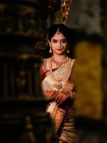 A glimpse of our beautiful client, a bride ready for her ceremony. Her traditional off-white silk saree with a rich border is the epitome of South Indian bridal elegance.