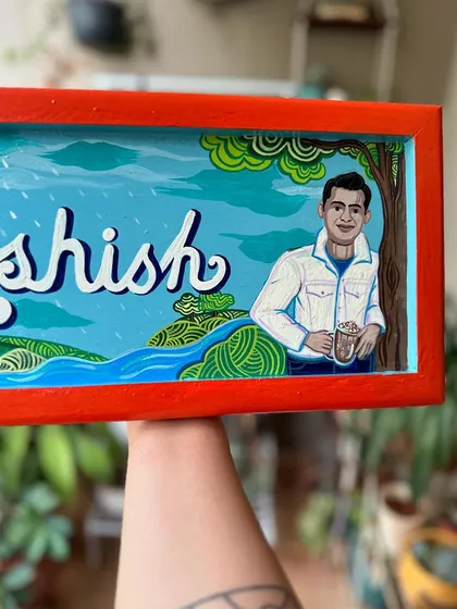 A custom name board created as a gift for a friend. It features his portrait along with things he loves, like nature and tennis.