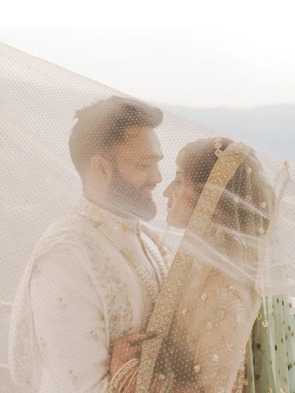 A dreamy, intimate portrait of the couple under the bride's veil, their faces close, sharing a private moment.