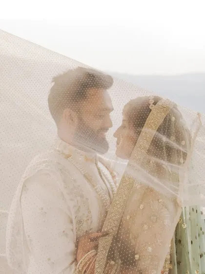 A tender moment between the couple, captured through the bride's veil, creating a soft and intimate portrait.