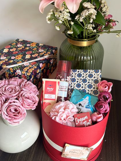 A vibrant red round box hamper for Mother's Day, including a Bath & Body Works fragrance mist, a lip tint, and a handcrafted diary.