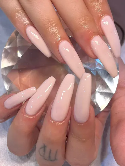 Long, coffin-shaped nails in a simple but elegant sheer nude polish. This look is all about the perfect shape and flawless application, creating a clean and sophisticated aesthetic.
