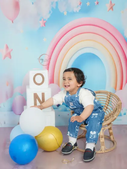 Pure delight! This candid photo captures a moment of laughter and play with balloons, showing the fun side of a first birthday session.