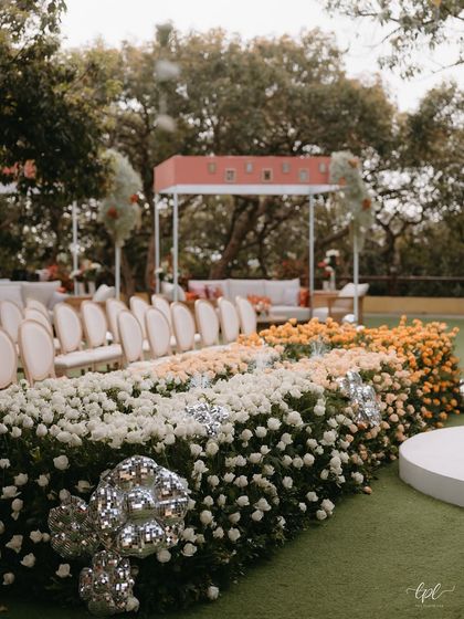 The ombré floral aisle, transitioning from white to yellow to orange roses, with clusters of disco balls adding a modern sparkle.