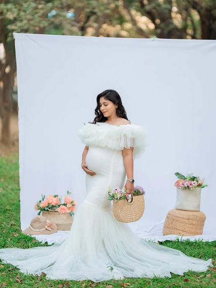 A full-length portrait of the mother-to-be, holding a basket of flowers. Props like these can add a lovely, personal touch to your outdoor maternity photoshoot.