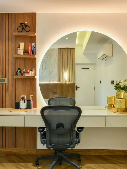 A workspace should inspire creativity and focus. This home office setup combines a chic dressing table with a functional workstation. The large, backlit circular mirror, clean lines, and warm wood accents create a space that is both elegant and highly productive.