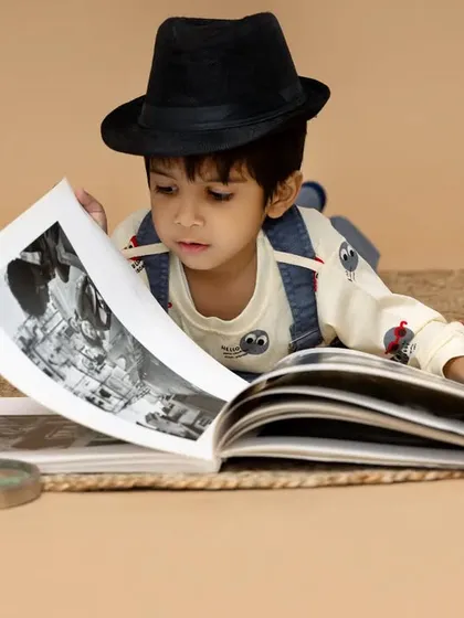 A young detective on the case. This creative setup with vintage books, a magnifying glass, and a fedora is a fun way to capture a child's inquisitive nature.