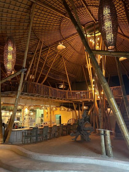 The intricate construction and warm lighting of this multi-story bamboo building in Bali showcase a mastery of sustainable architecture.