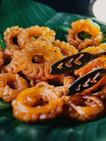 Taking "kuch meetha ho jaaye" very seriously with these crispy, golden imartis. Served fresh on a banana leaf, they are a traditional favourite that brings joy to any celebration.