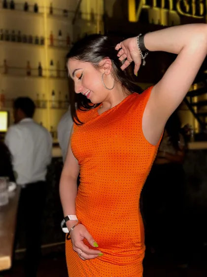 A candid, dancing shot in a bright orange dress, capturing a moment of pure fun and energy on the dance floor.