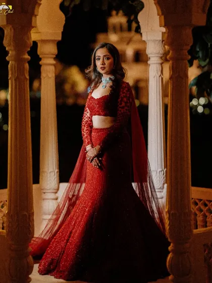 A breathtaking solo portrait of the bride in her vibrant red sangeet outfit, framed by the arches of the venue.