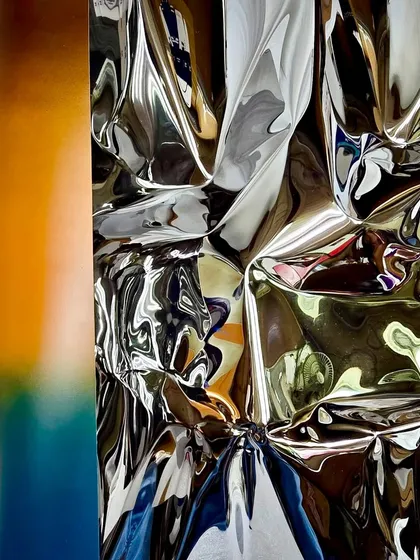 A detail of "Meteor 151," where the polished steel meets a warm, sunset-like gradient, showing the transition from rigid metal to fluid color.